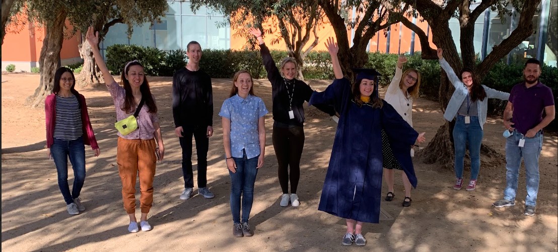 Group photo of the Barile lab standing 6 feet apart outside RMI under the olive trees after Amanda's graduation